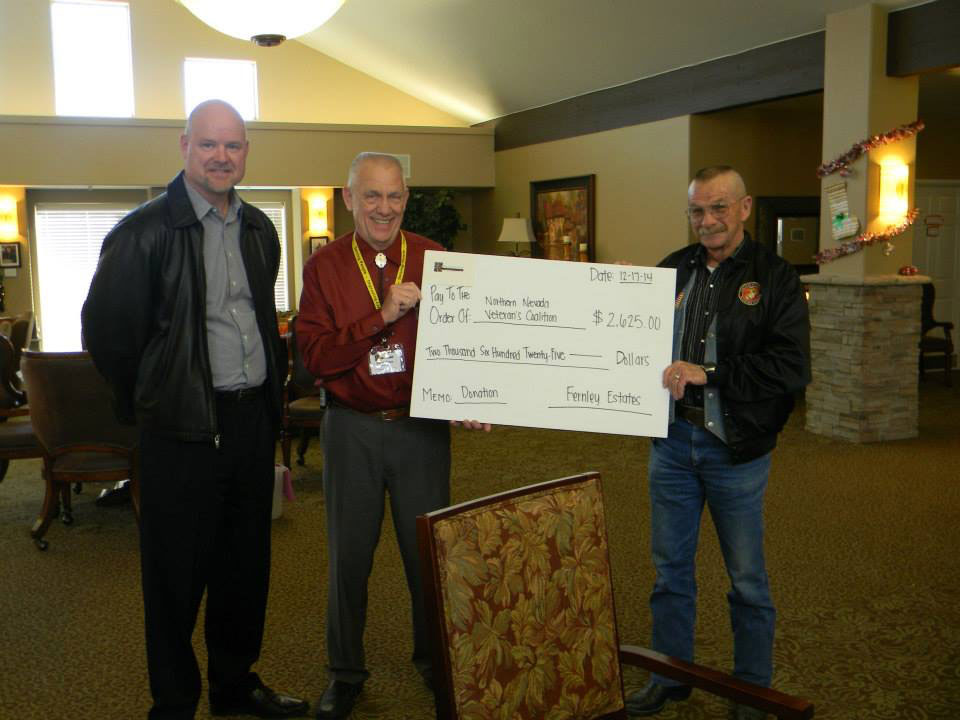 Three men standing in the community room holding a check.